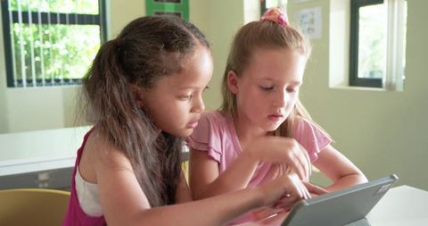Young students collaborating on tablet in bright classroom for interactive learning