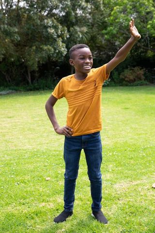 Playful African American Boy Waving in Garden Outdoors