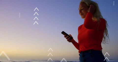 Caucasian Woman Enjoying Smartphone at Sunset with Digital Arrows Concept