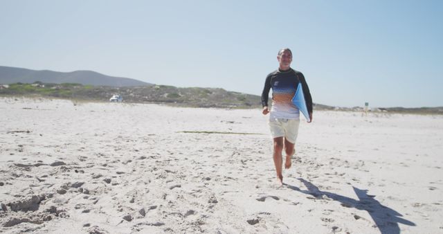 Surfer with board running on sandy beach during bright sunny day - Download Free Stock Images Pikwizard.com