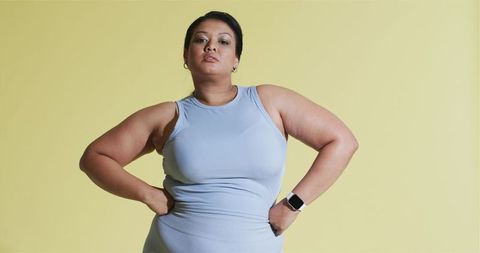 Confident mid adult woman in activewear on pastel background