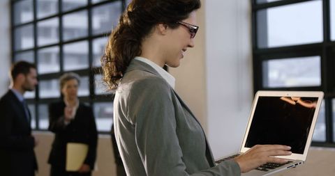 Confident businesswoman engaging with laptop in office environment