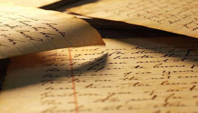 Curling aged lined pages with cursive handwriting, red margin and warm sepia light texture
