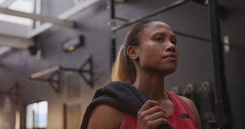 Determined female athlete holding towel in modern gym