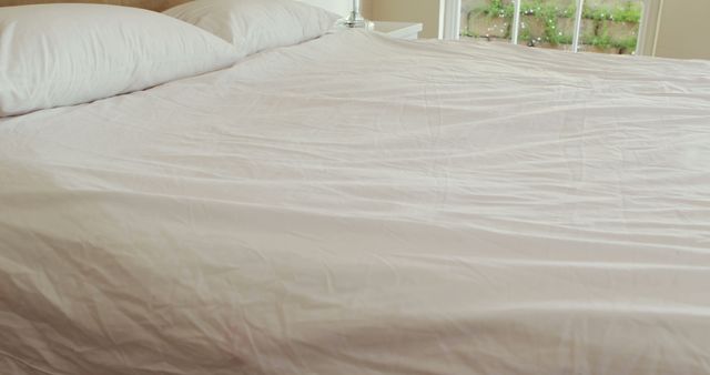 Cozy made bed with white sheets in sunlit bedroom - Download Free Stock Photos Pikwizard.com