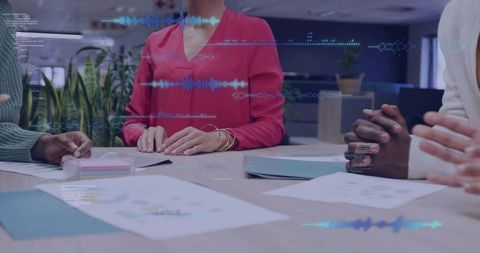 Leading woman in red blouse resting hands on table during team meeting with charts