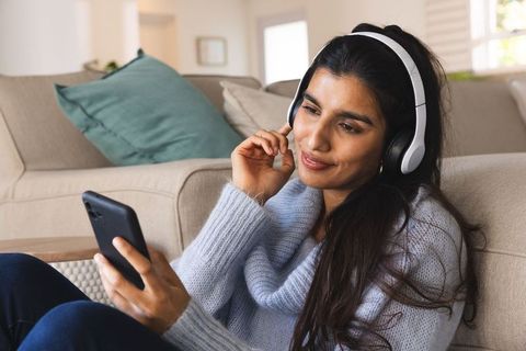 South Asian Woman Enjoying Music on Smartphone with Headphones at Home