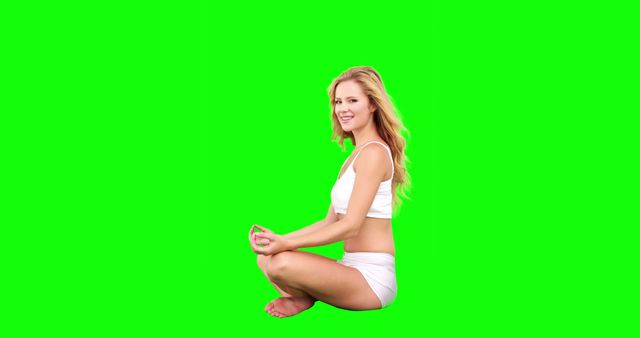 Woman practicing yoga in lotus position with a green screen background. Great for implementing into fitness and wellness content, or for editing purposes in video and digital media projects. Ideal for promoting a healthy lifestyle, relaxation, and balance. Suitable for use in advertisements or tutorials on yoga and meditation.