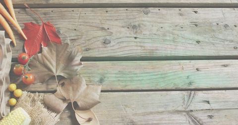 Rustic autumn harvest flatlay on weathered wooden planks with carrots tomatoes corn