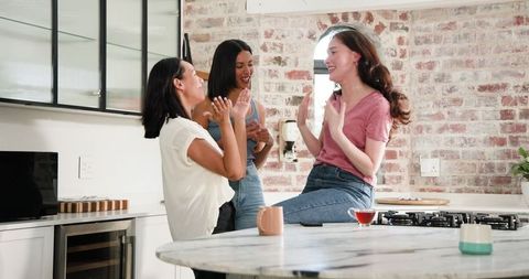 Friends celebrating engagement over tea in bright modern kitchen
