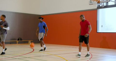 African american men practicing basketball drills in bright indoor gym court