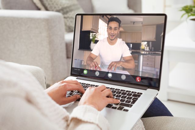 Biracial smiling businessman talking to caucasian female colleague on video call. unaltered, work from home, business, wireless technology, working, teamwork and office concept.