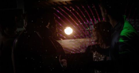 Backlit party van interior with silhouetted passengers, laser dots and sequined woman