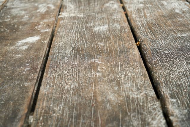 Detailed close-up of weathered wooden planks showcasing natural textures and cracks. Ideal for backgrounds in graphic design projects, presentations related to construction or woodworking, and emphasizing rustic themes in prints.