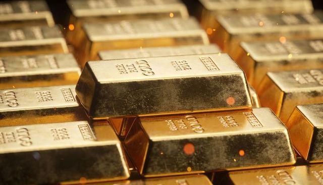 Stacked gold bars gleaming in vault close-up showing bullion markings and reflections