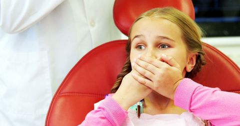 Anxious young patient covering mouth at dentist office