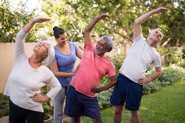 Group of seniors stretching with assistance from a trainer in a park. Ideal for promoting senior fitness, healthy lifestyle, and outdoor activities. Useful for health and wellness campaigns, fitness programs, and senior care services.