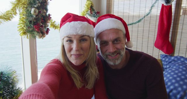 Happy Couple Enjoying Christmas at Home by the Sea Wearing Santa Hats - Download Free Stock Images Pikwizard.com