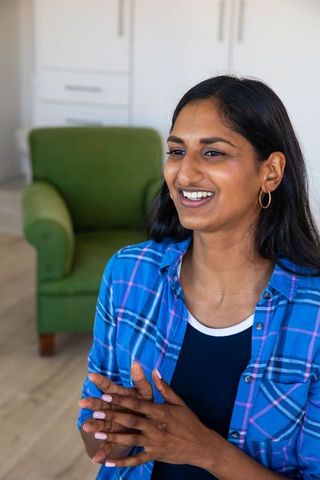 Confident indian woman gesturing in cozy living room interior