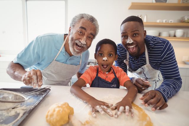 Multi-generation family enjoying a playful baking session in kitchen. Grandfather, father, and son covered in flour, smiling and having fun while preparing dough. Ideal for illustrating family bonding, cooking activities, domestic life, and the joy of family time in home settings.