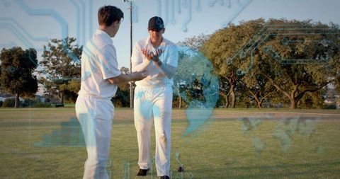 Cricketers holding red ball while analyzing digital data overlay on outdoor practice field