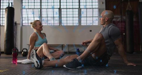 Couple resting after intense gym session in boxing studio, cooling down on rubber mat