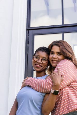 Two african american women hugging at home entrance showing friendship and support