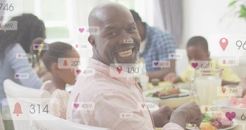 Multigenerational family dining with man smiling and social media notification overlays