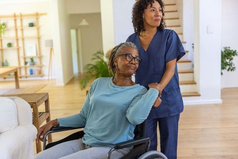 African American Caregiver Assisting Elderly Woman in Living Room