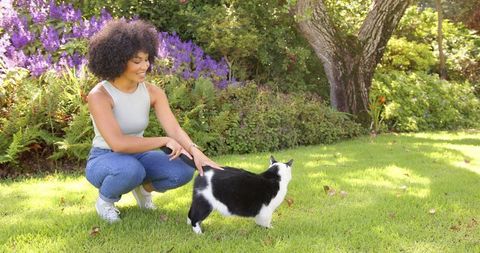 Woman Bonding with Black and White Cat in Lush Garden