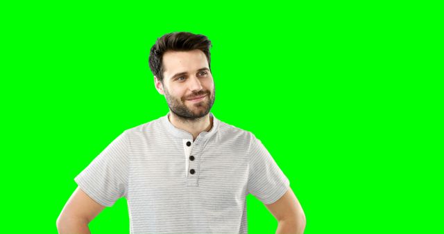 This shot of a confident young man with his hands on his hips standing against a green screen background can be used for various editing and compositing purposes. Ideal for visual presentations, educational videos, advertisements, and promotional content where the individual can be cropped and placed in different settings.