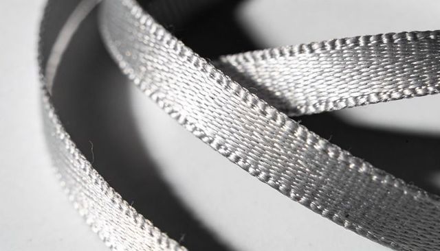 Silver satin ribbon looping with metallic sheen and woven texture showing loose fibers