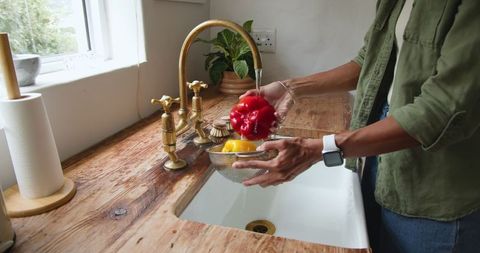 Washing fresh bell peppers at rustic kitchen sink