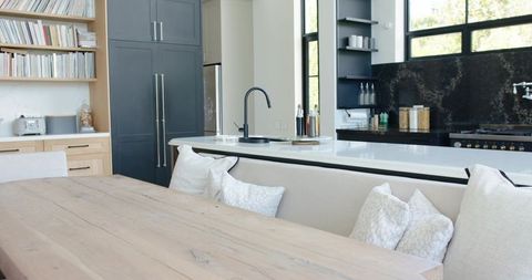 Minimal modern kitchen dining area with light wood table, built-in bench, soft pillows