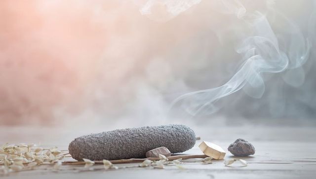 Minimal spa still life with pumice stone, swirling incense smoke and rose crystal gems