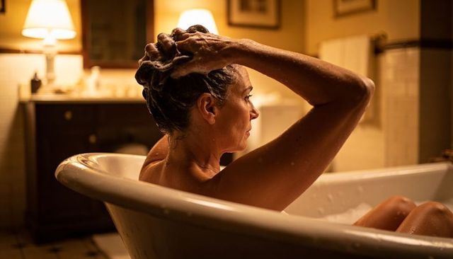Woman washing hair in clawfoot tub at home evening bath relaxation and self-care