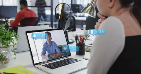 Woman joining video call at modern open-plan office desk with engagement overlays, headset