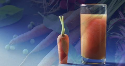 Fresh carrot juice with whole carrots on blue background