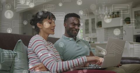 Couple using laptop for social chat and online collaboration while relaxing on couch