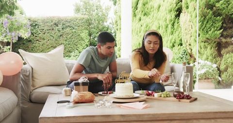 Couple celebrating birthday with cake on sunny patio