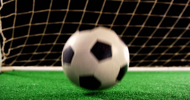 Soccer ball in motion near the goalpost on green field captures the essence of sport and action. Ideal for promoting soccer events, sports gear, and athletic programs. Great for announcements, posters, and sports-based digital content.