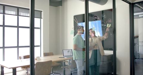 Colleagues brainstorming with digital whiteboard in modern office