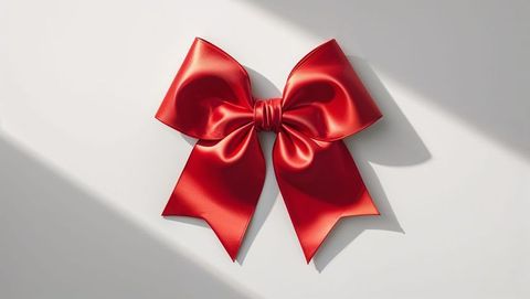 Elegant red satin gift bow on smooth white surface