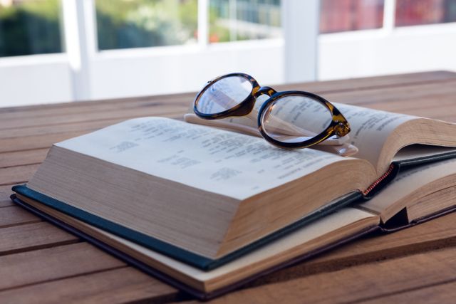 Close-up of spectacles on open book at desk
