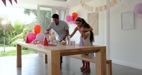 Family setting up birthday table with balloons and party theme