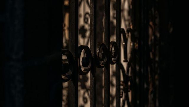 Wrought Iron Gate Casting Warm Afternoon Light and Ornamental Shadow Patterns