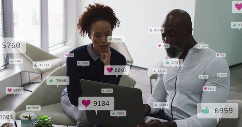 Coworkers collaborating over laptop in modern office lounge with social engagement overlays