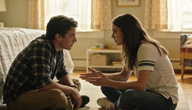 Young couple sitting on bedroom rug having intimate conversation in sunlit cozy room