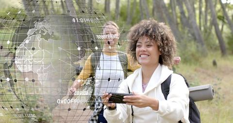 Smiling hiker holding smartphone navigating forest trail with backpack and rolled mat, ar map