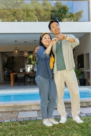 Couple holding house keys by pool celebrating first-time homeownership and new life